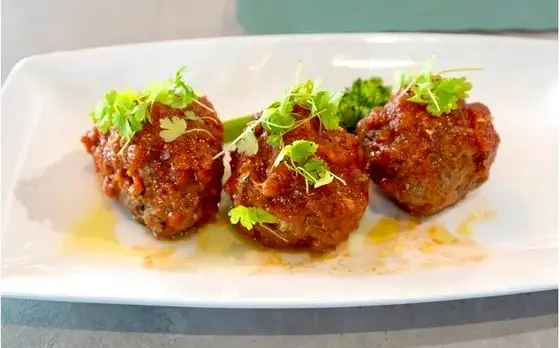Tavern Meatballs in San Marzano sugo with Grana Padano and microgreens.